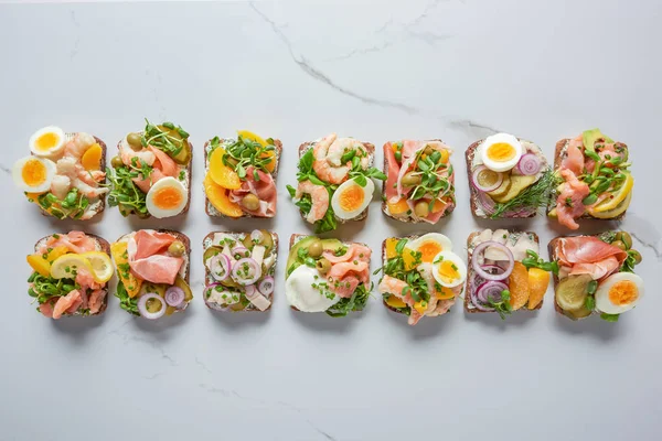 Vue de dessus de délicieux sandwichs danois smorrebrod sur la surface de marbre blanc — Photo de stock