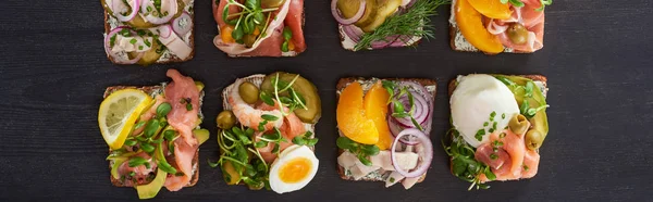 Panoramic shot of fresh smorrebrod sandwiches on grey surface — Stock Photo