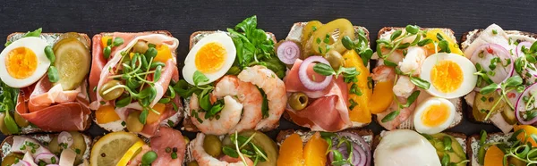 Panoramic shot of traditional smorrebrod sandwiches with boiled eggs on grey surface — Stock Photo