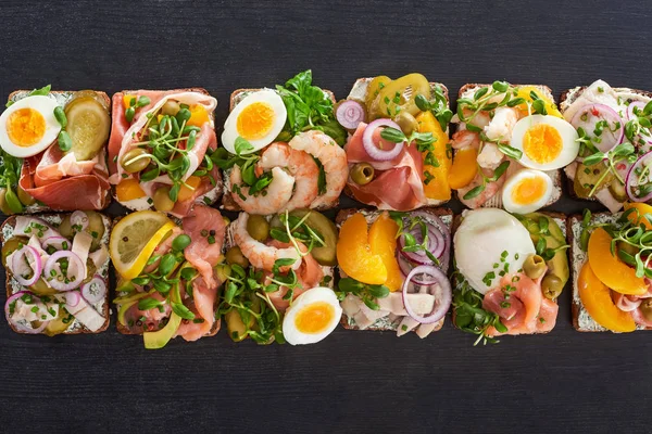 Top view of rye bread with fresh smorrebrod sandwiches on grey surface — Stock Photo