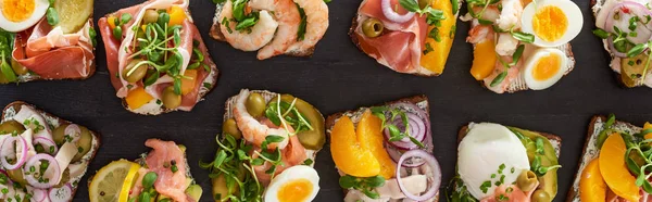 Panoramic shot of rye bread with traditional smorrebrod sandwiches on grey surface — Stock Photo