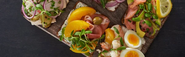 Panoramic shot of cutting board with fresh danish smorrebrod sandwiches on grey surface — Stock Photo