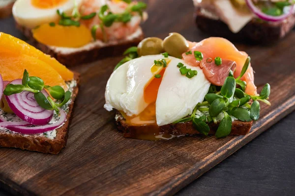 Close up of fresh smorrebrod sandwich with poached egg on wooden cutting board — Stock Photo