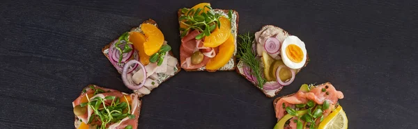 Panoramic shot of tasty smorrebrod sandwiches with canned peaches on grey surface — Stock Photo