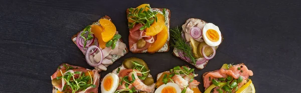 Panoramic shot of rye bread with smorrebrod sandwiches on grey — Stock Photo