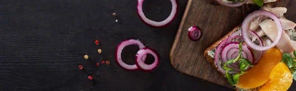 Panoramic shot of rye bread with smorrebrod sandwich with herring fish and canned peaches on grey surface — Stock Photo