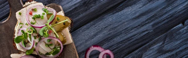 Panoramic shot of rye bread with smorrebrod sandwich on blue woooden surface — Stock Photo