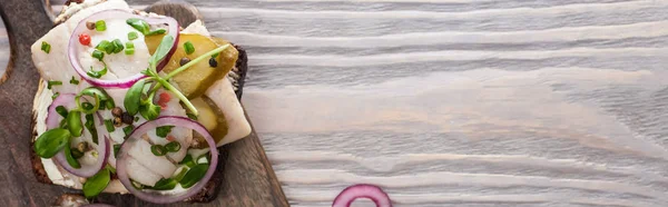 Panoramic shot of rye bread with fresh smorrebrod sandwich on wooden surface — Stock Photo