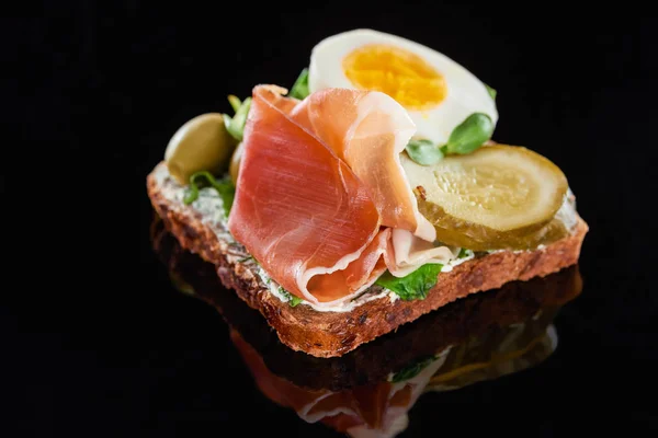 Close up of rye bread with tasty ham on smorrebrod sandwich on black — Stock Photo