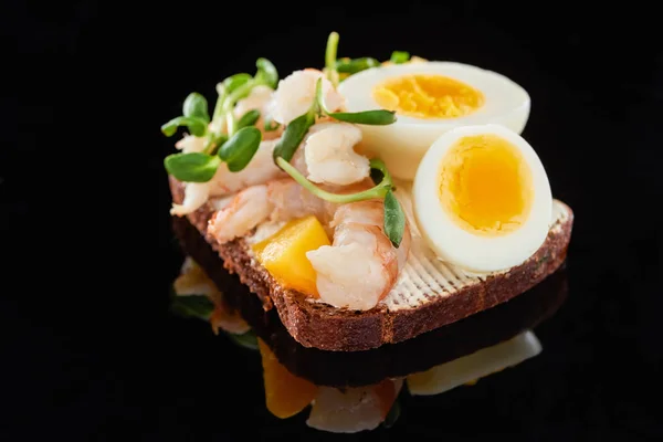 Закрыть ржаной хлеб с вкусными креветками на сэндвиче со сморребродом на черном — стоковое фото