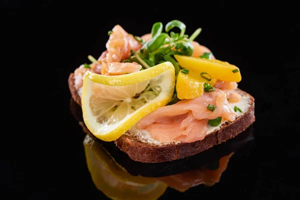 Gros plan de saumon sur savoureux sandwich smorrebrod sur noir — Photo de stock