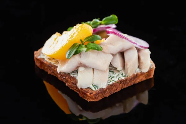 Close up of herring fish on delicious smorrebrod sandwich on black — Stock Photo