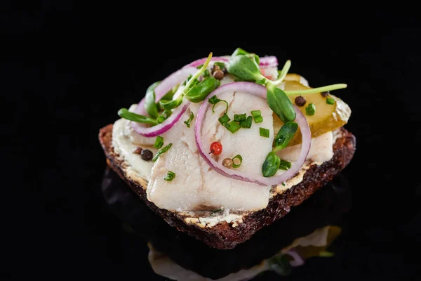 Perto de cebolas e peixe de arenque em sanduíche de smorrebrod dinamarquês no preto — Fotografia de Stock