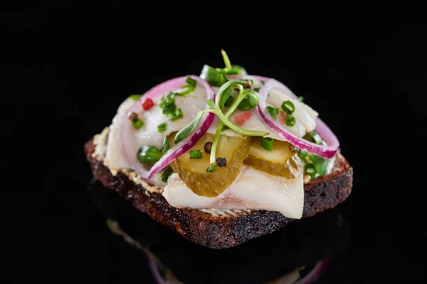 Primer plano de pescado de arenque en sándwich de smorrebrod danés en negro - foto de stock