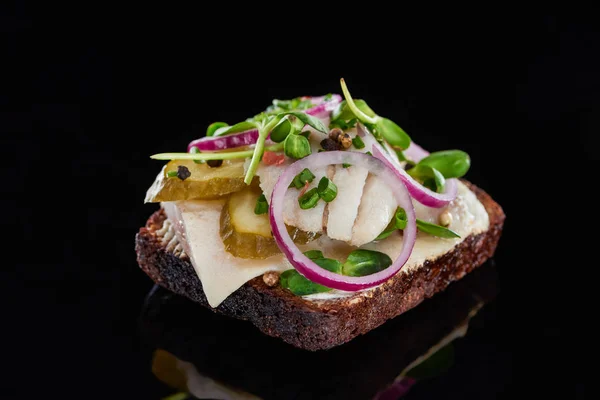 Primer plano de pescado arenque en sabroso smorrebrod sándwich danés en negro - foto de stock