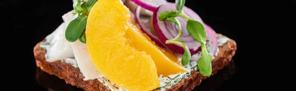 Panoramic shot of herring fish and canned peaches on danish smorrebrod sandwich on black — Stock Photo