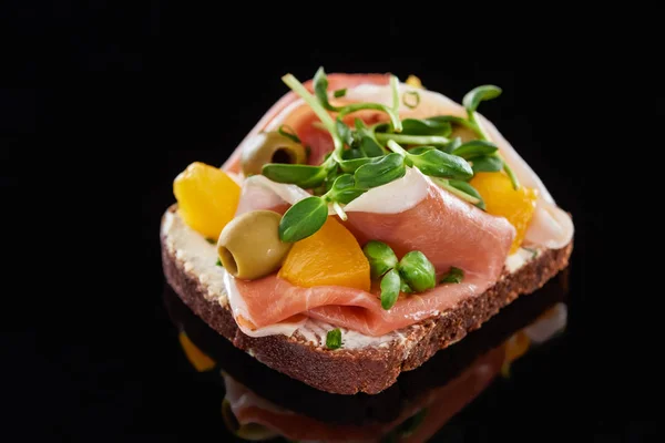 Selektiver Fokus von Schinken und Oliven auf gekochtem dänischem Smorrebrod-Sandwich auf Schwarz — Stockfoto