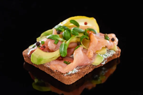 Nahaufnahme von Avocado in der Nähe von Lachs auf dänischem Smorrebrod-Sandwich auf schwarz — Stockfoto