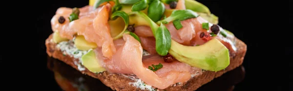 Panoramic shot of avocado near salmon on danish smorrebrod sandwich on black — Stock Photo