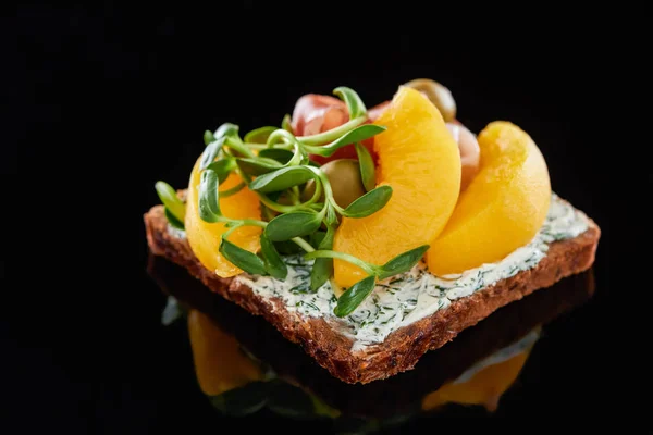Selektiver Fokus von Dosenpfirsichen auf dänischem Smorrebrod-Sandwich auf Schwarz — Stockfoto