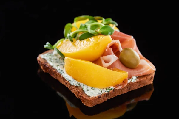 Selektiver Fokus von Schinken und Pfirsichen aus Dosen auf dänischem Smorrebrod-Sandwich auf Schwarz — Stockfoto