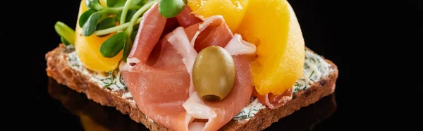 Panoramic shot of ham and canned peaches on danish smorrebrod sandwich on black — Stock Photo