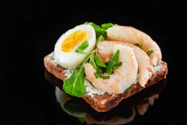 Close up de ovo cozido perto de camarões em delicioso sanduíche dinamarquês smorrebrod em preto — Fotografia de Stock