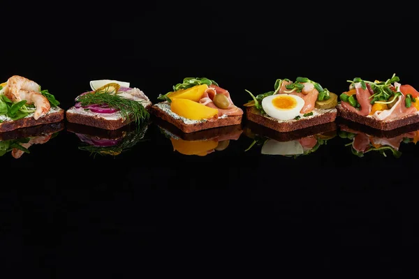 Pão de centeio com sanduíches smorrebrod dinamarqueses saborosos em preto — Fotografia de Stock
