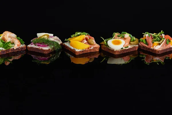 Rye bread with tasty danish smorrebrod sandwiches on black — Stock Photo