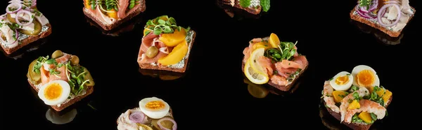 Panoramic shot of rye bread with tasty danish smorrebrod sandwiches on black — Stock Photo
