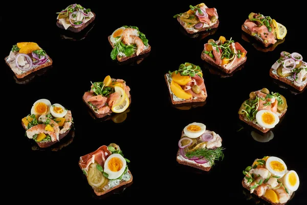 Rye bread with tasty danish smorrebrod sandwiches on black — Stock Photo