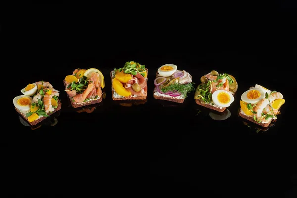 Rye bread with prepared danish smorrebrod sandwiches on black — Stock Photo