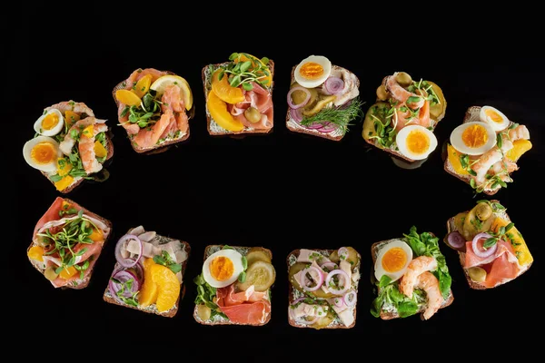 Vista superior del pan de centeno con sándwiches de smorrebrod danés preparados aislados en negro - foto de stock