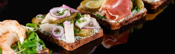 Panoramic shot of fresh smorrebrod sandwiches on black — Stock Photo