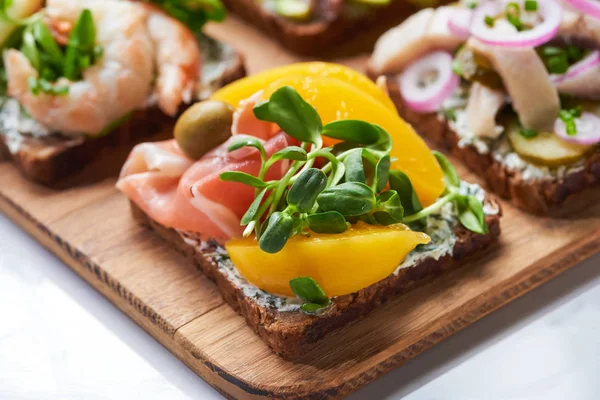 Close up of canned peaches on delicious smorrebrod sandwich on wooden cutting board — Stock Photo