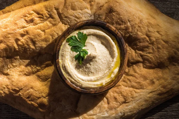 Top view of delicious hummus in bowl on fresh baked pita — Stock Photo