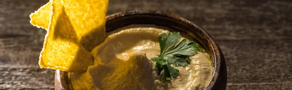 Köstlicher Hummus in Schüssel mit Nachos auf rustikalem Holztisch, Panoramaaufnahme — Stockfoto