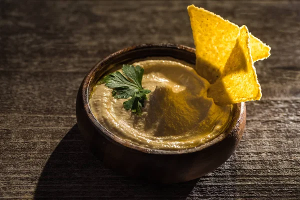 Delicious hummus in bowl with nachos on wooden rustic table — Stock Photo