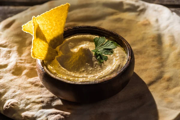 Hummus delicioso com nachos na tigela no pita cozido no forno fresco — Fotografia de Stock