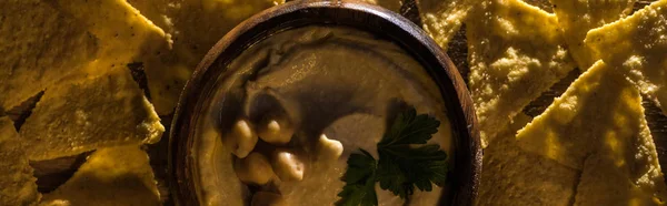 Top view of delicious hummus with chickpeas in bowl near nachos, panoramic shot — Stock Photo