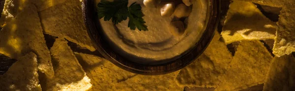 Draufsicht auf köstlichen Hummus mit Kichererbsen in Schüssel in der Nähe von Nachos, Panoramaaufnahme — Stockfoto