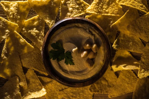 Vista superior de delicioso hummus com grão de bico em tigela perto de nachos — Fotografia de Stock