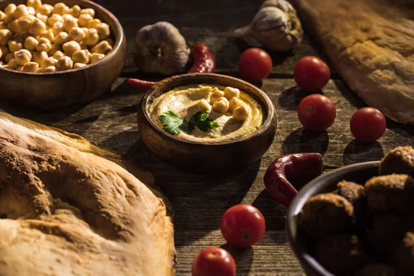 Delicioso falafel, húmus, grão de bico, pita, legumes e especiarias em mesa rústica de madeira — Fotografia de Stock