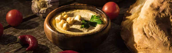 Délicieux houmous, pita, légumes et épices sur table rustique en bois, vue panoramique — Photo de stock