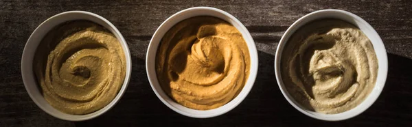 Top view of delicious assorted hummus on wooden rustic table, panoramic shot — Stock Photo