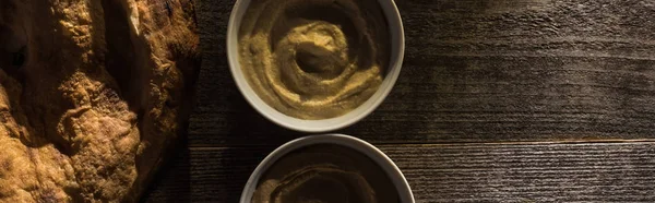 Draufsicht auf köstlich sortierten Hummus und frisch gebackene Pita auf rustikalem Holztisch, Panoramaaufnahme — Stockfoto