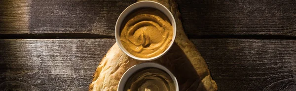 Top view of delicious assorted hummus on fresh baked pita on wooden rustic table, panoramic shot — Stock Photo