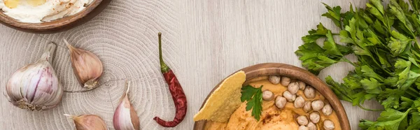 Vista superior de delicioso hummus com grão de bico, nacho em tigela perto de especiarias e salsa em mesa de madeira bege, tiro panorâmico — Fotografia de Stock