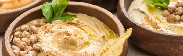 Close up view of delicious hummus with chickpeas and nacho in bowls, panoramic shot — Stock Photo