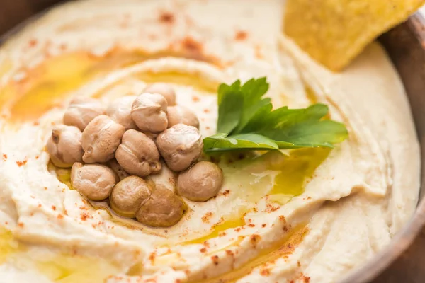 Vue rapprochée de délicieux houmous aux pois chiches et nacho dans un bol — Photo de stock